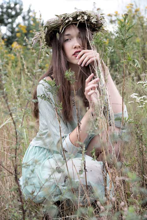 Delikatna, młoda kobieta siedzi na trawie
